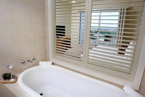 a white bath tub in a bathroom with a window at Mantra on Salt Beach in Kingscliff