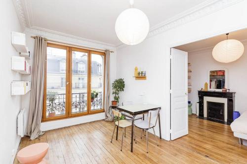 un salon blanc avec une table et des chaises dans l'établissement Charmant appartement avec vue, à Paris