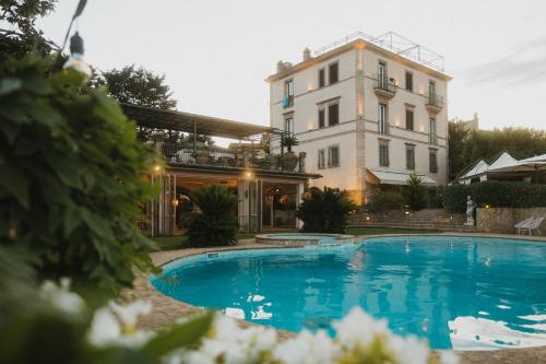 a hotel with a swimming pool in front of a building at Villa Clodia Relais in Manziana