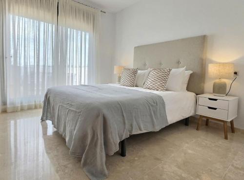 a white bedroom with a large bed and a lamp at Gorgeous 3-Bedroom Penthouse with Expansive Terrace in Casares Costa in Buenas Noches