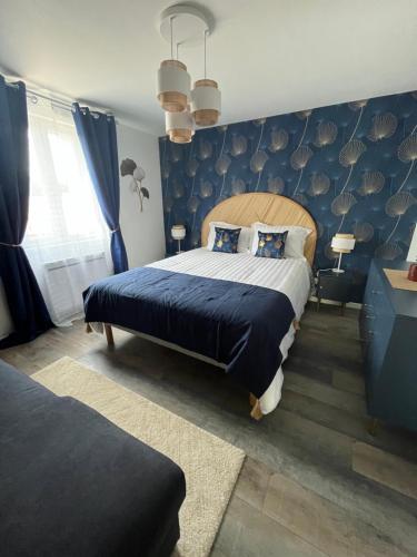 a bedroom with a large bed with a blue wall at l'HIRONDELLE in Les Goths
