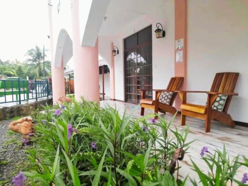 a patio with two chairs and flowers in front of a building at Pangea Lodge with Shared Pool at the Heart of Manzanillo in Manzanillo