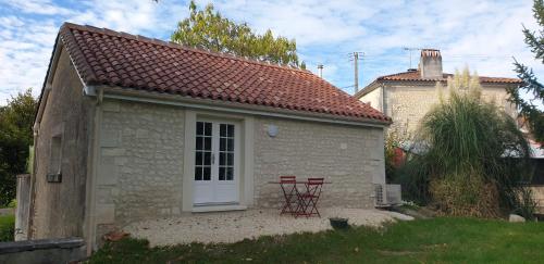 two red chairs sitting outside of a small house at Gîte du moulin de la motte in Ambleville