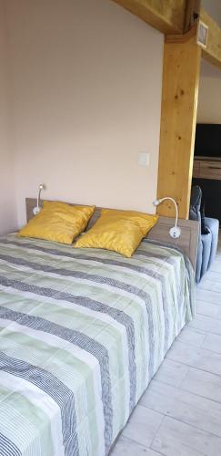 a bed with two yellow pillows on top of it at Gîte du moulin de la motte in Ambleville