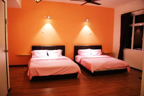 two beds in a room with orange walls at Shamrock Seaview 11 Villa in Batu Ferringhi