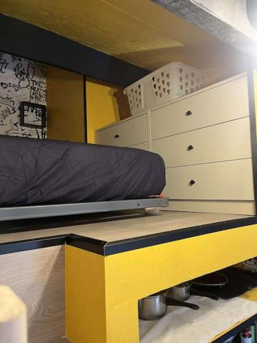 - une chambre avec un lit, une commode et un banc jaune dans l'établissement Studio Pop Art Villeneuve, à Villeneuve-lès-Avignon