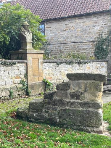 a statue of a man sitting on top of a stone wall at The Little House in Kilburn
