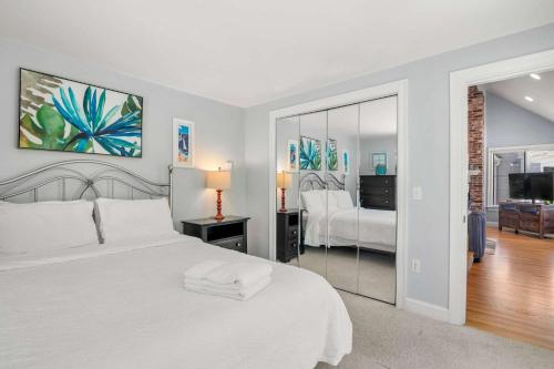 a white bedroom with a bed and a mirror at Beautifully Renovated w Access to Beach in Chatham