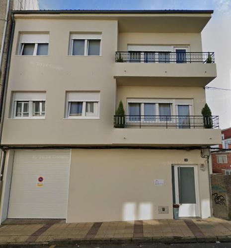 a white building with a garage and a balcony at Gallaecia in Arzúa