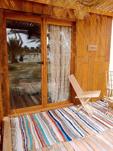 a wooden porch with a bench and a glass door at Garden12 Outdoor & More in Douz