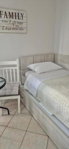 a bedroom with a white bed and a chair at Sunset Apartment in Shëngjin