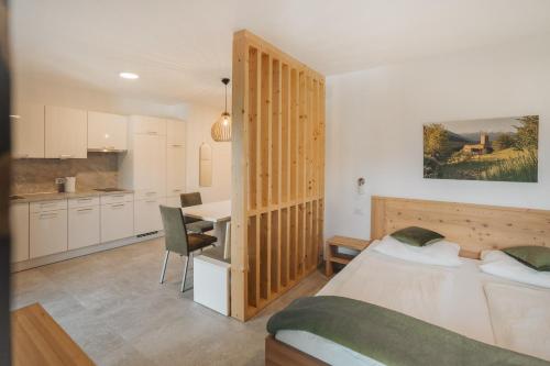 a bedroom with a bed and a desk and a kitchen at Residence Karpoforus in Laces