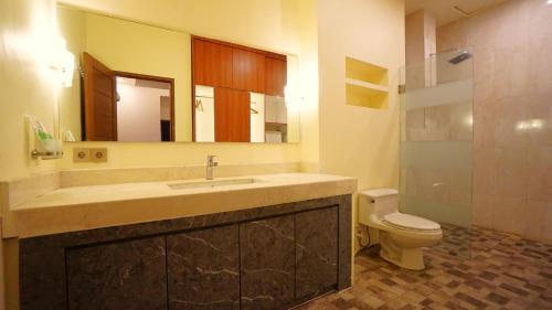 a bathroom with a sink and a toilet and a mirror at BAGUS Guest House in Legian