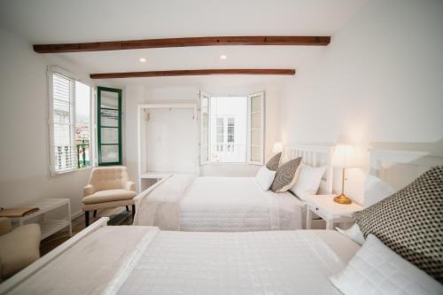 a white bedroom with two beds and a chair at Hotel Boutique San Luis Mongui in Monguí
