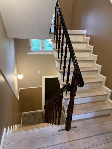 a staircase in a home with white stairs and wooden railings at Byhuset - Haven 10 in Vejle