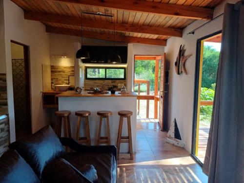 a kitchen and living room with a counter and stools at LOBOS DEL BOSQUE CON JACUZZi in Punta Del Diablo