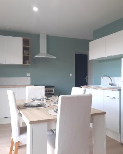 - une cuisine avec une table en bois et des chaises blanches dans l'établissement Gîte de la Forêt de Poyant, à Lussant