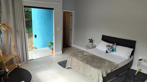 a bedroom with a bed and a sliding glass door at Studio Flor do Mato - Onde a natureza te encontra in Itapema