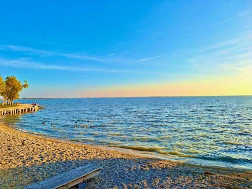 a beach with a wooden pier and the water at Apartments C'EST LA SEA - Whirlpool-Suite oder Dachterrassen-Suite in Neusiedl am See