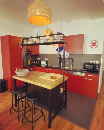 une cuisine avec des placards rouges et un îlot avec des tabourets de bar dans l'établissement T3 Rue de Republique - Panier, à Marseille