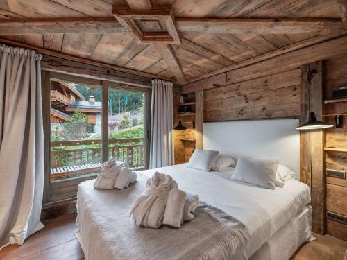 une chambre avec un grand lit avec des serviettes dessus dans l'établissement Chalet spacieux, skis aux pieds, cheminée, parking, WiFi - FR-1-565-114, à Les Allues