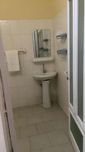 a white bathroom with a sink and a mirror at Keur Massar Tolou Laye WADE in Niadyorane