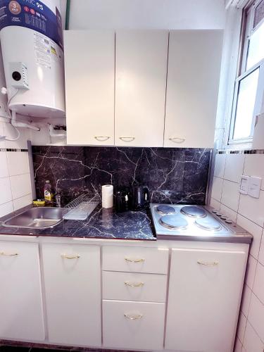 a small kitchen with white cabinets and a sink at Amplio monoambiente en Microcentro in Buenos Aires