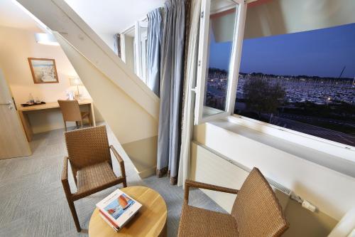 a room with two chairs and a table and a large window at Trinite Hotel in La Trinité-sur-Mer