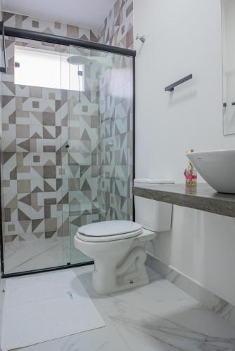 a bathroom with a toilet and a glass shower at Residencial Solar do Pescador in São Sebastião