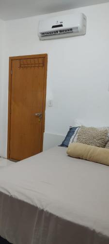 a bedroom with a white bed and a wooden door at Studio 202 Cop 30 in Belém