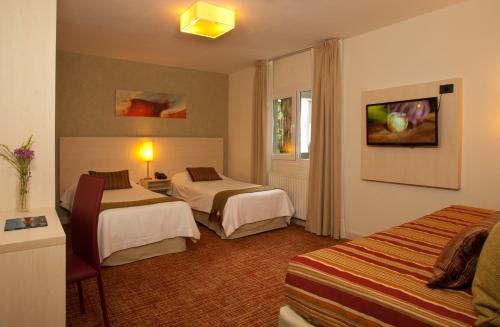 a hotel room with two beds and a tv at Hotel De Los Andes in Ushuaia