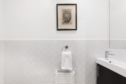 a white bathroom with a sink and a mirror at Paddington Apartment By Morethanstays in London