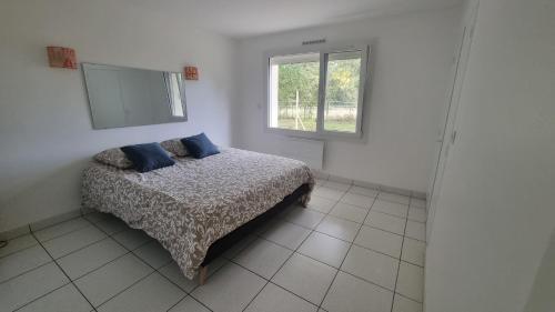 une chambre avec un lit avec des oreillers bleus et une fenêtre dans l'établissement Le Charmant T3 avec Jardin Privé, à Flourens