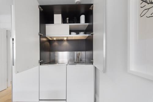 a kitchen with white cabinets and a silver sink at Crawford Street Apartment By Morethanstays in London