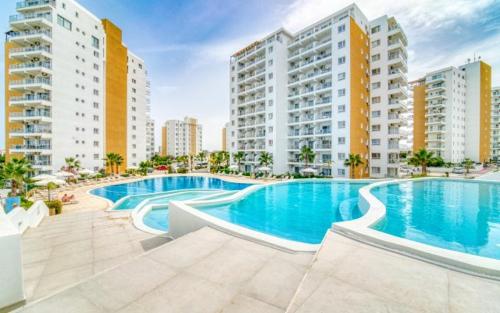 ein großer Pool mit Gebäuden im Hintergrund in der Unterkunft 1 Bedroom Apartment Long Beach İskele in Saint Yeorgios