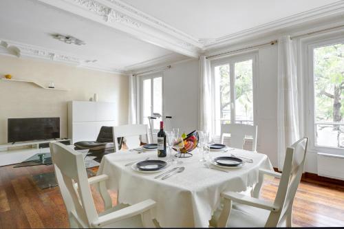 une salle à manger blanche avec une table et des chaises dans l'établissement Place de la République - Suite Haussmannienne, à Paris