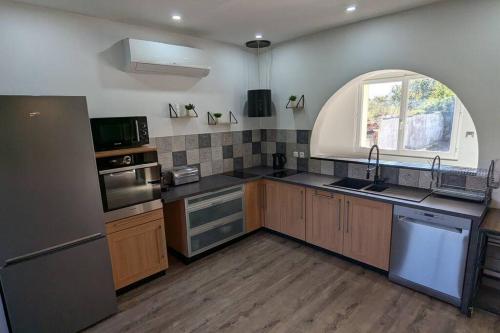 d'une cuisine avec un évier et une fenêtre cintrée. dans l'établissement #Maison chaleureuse sur les hauteurs d'Aubiac#, à Aubiac