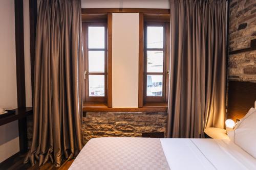 a hotel room with a bed and two windows at N'SOKAK Boutique Hotel in Gjirokastër
