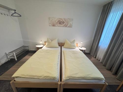 two beds in a room with two tables at Hotel Hildesheimer Hof in Harsum