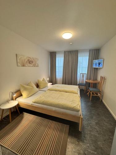 a bedroom with a bed and a table and chairs at Hotel Hildesheimer Hof in Harsum