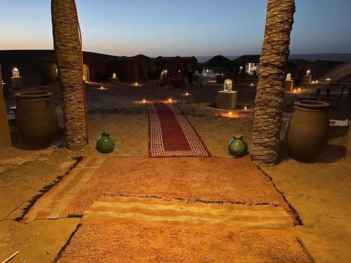 a pathway in the middle of a desert with palm trees at Desert Erg Chegaga Camp in El Gouera