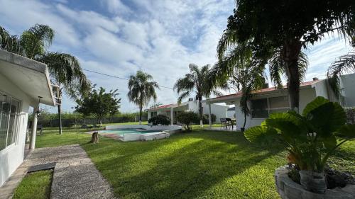 a backyard of a house with a pool and palm trees at Villa Residencial Aéreo Albatros in Tequesquitengo