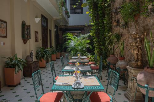 a row of tables in a room with plants at Hotel Casa La Fe in Cartagena de Indias