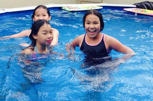 Trois jeunes filles dans une piscine dans l'établissement Aalton Motel, à Christchurch