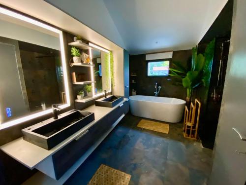 a bathroom with two sinks and a bath tub at La Cour de la Forêt in Saint-Mars-de-Coutais