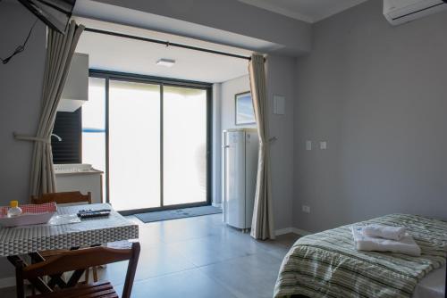 a bedroom with a bed and a table and a window at Residencial Solar do Pescador in São Sebastião