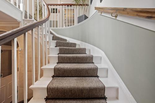 a winding staircase with white railings andbrown carpet at Sleeping Bear Hotels Dorchester in Dorchester