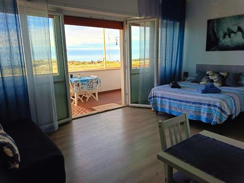 a bedroom with a bed and a balcony with a table at Mare e Relax 1 Melody Sea Front 10' da FCO Airport in Fiumicino