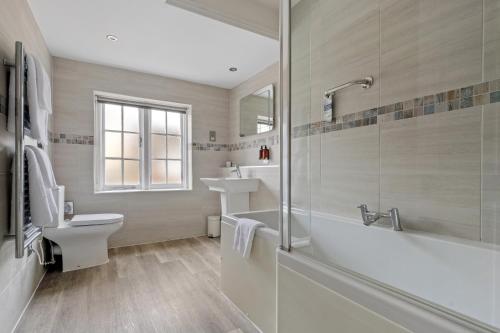 a bathroom with a tub and a toilet and a sink at Sleeping Bear Hotels Dorchester in Dorchester