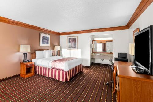 a hotel room with a bed and a flat screen tv at Scottish Inns - Decatur in Decatur